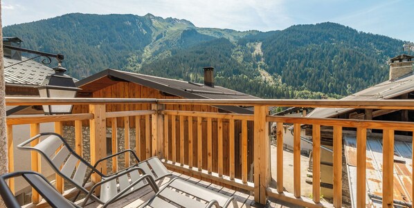 Une terrasse en bois avec des rampes de protection en métal, offrant une vue sur un paysage montagneux.