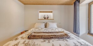 Une chambre à coucher comprenant un lit, une table de chevet, une fenêtre avec des rideaux et une étagère murale décorée de divers objets.