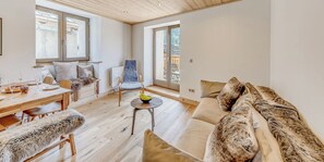 Un salon moderne avec un plancher en bois, un canapé, une table à manger dressée pour deux personnes et une chaise.