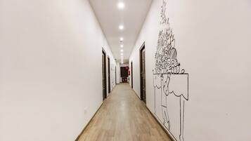 Un pasillo con piso de madera, paredes blancas y un mural en la pared derecha.