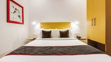 Habitación de hotel con cama, mesitas de noche, armario y un cuadro en la pared.