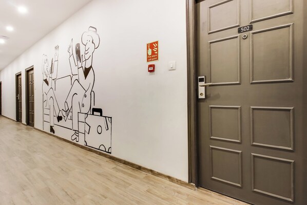 A hallway with a wall mural, a fire alarm pull station, and a door labeled '502'. - Townhouse Meridian Regency (Hyderabad)