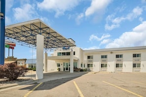 A hotel with a covered parking area and a building with multiple windows and doors.