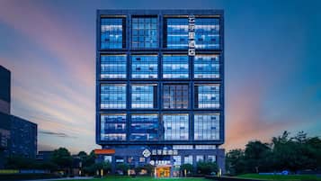 Un edificio moderno con varios pisos, amplios ventanales y un césped bien cuidado al frente.