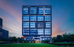 Un edificio moderno con varios pisos, amplios ventanales y un césped bien cuidado al frente.