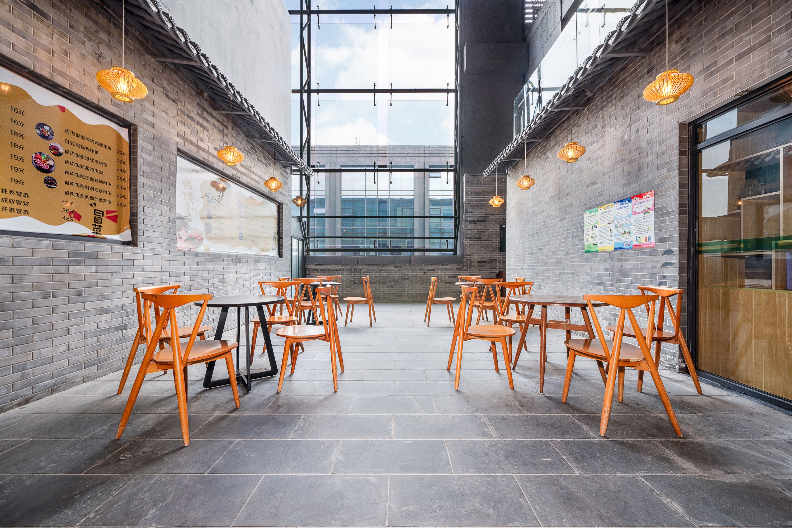 Un vaste espace intérieur aux murs de briques, avec des chaises et des tables en bois disposées pour accueillir les clients.
