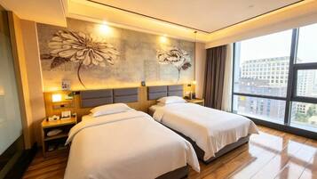 Habitación de hotel con dos camas, un ventanal grande y una pared con diseño floral.