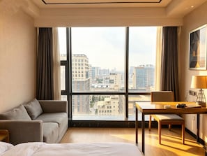 Una habitación de hotel con un ventanal grande, un sofá, un escritorio y una cama.