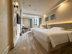 Una habitación de hotel con dos camas, televisión y ventana con cortinas.