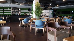 A modern restaurant with wooden tables and chairs, a bar area, and a green wall. - Kudat Golf and Marina Resort (Kudat)