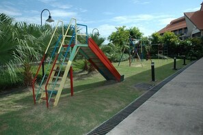 A playground with a slide and climbing structures, surrounded by grass and palm trees. - Kudat Golf and Marina Resort (Kudat)