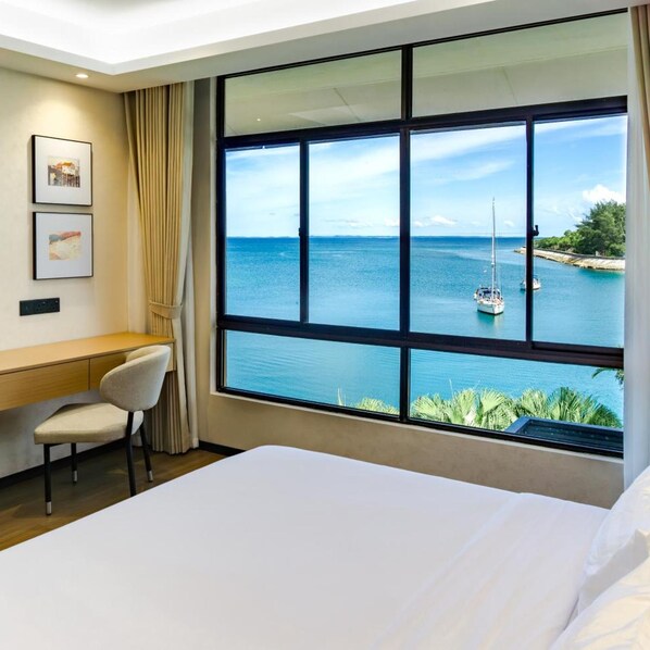 A hotel room with a large window offering a view of the sea and a sailboat. - Kudat Golf and Marina Resort (Kudat)