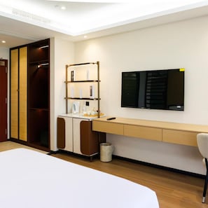 Een hotelkamer met een bed, een bureau, een kledingkast en een televisie.