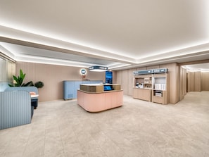 A modern reception area with a counter, seating, and a digital display. - Hanting Hotel Xihu Xiebai (Hangzhou)
