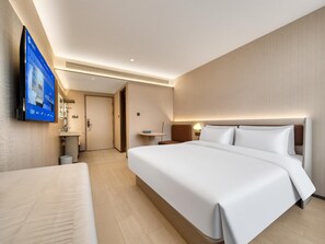 A hotel room with a large bed, bedside tables, a TV mounted on the wall, and a door leading to a bathroom. - Hanting Hotel Xihu Xiebai (Hangzhou)