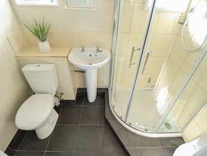 A bathroom with a toilet, sink, and glass-enclosed shower. - Cherry Park Retreat (Skegness)