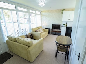 A living room with a sofa, a coffee table, and a television. - Cherry Park Retreat (Skegness)