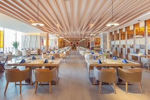 A spacious dining area with multiple tables and chairs, a modern ceiling design, and large windows allowing natural light. - Argyle Hotel (Honghe)
