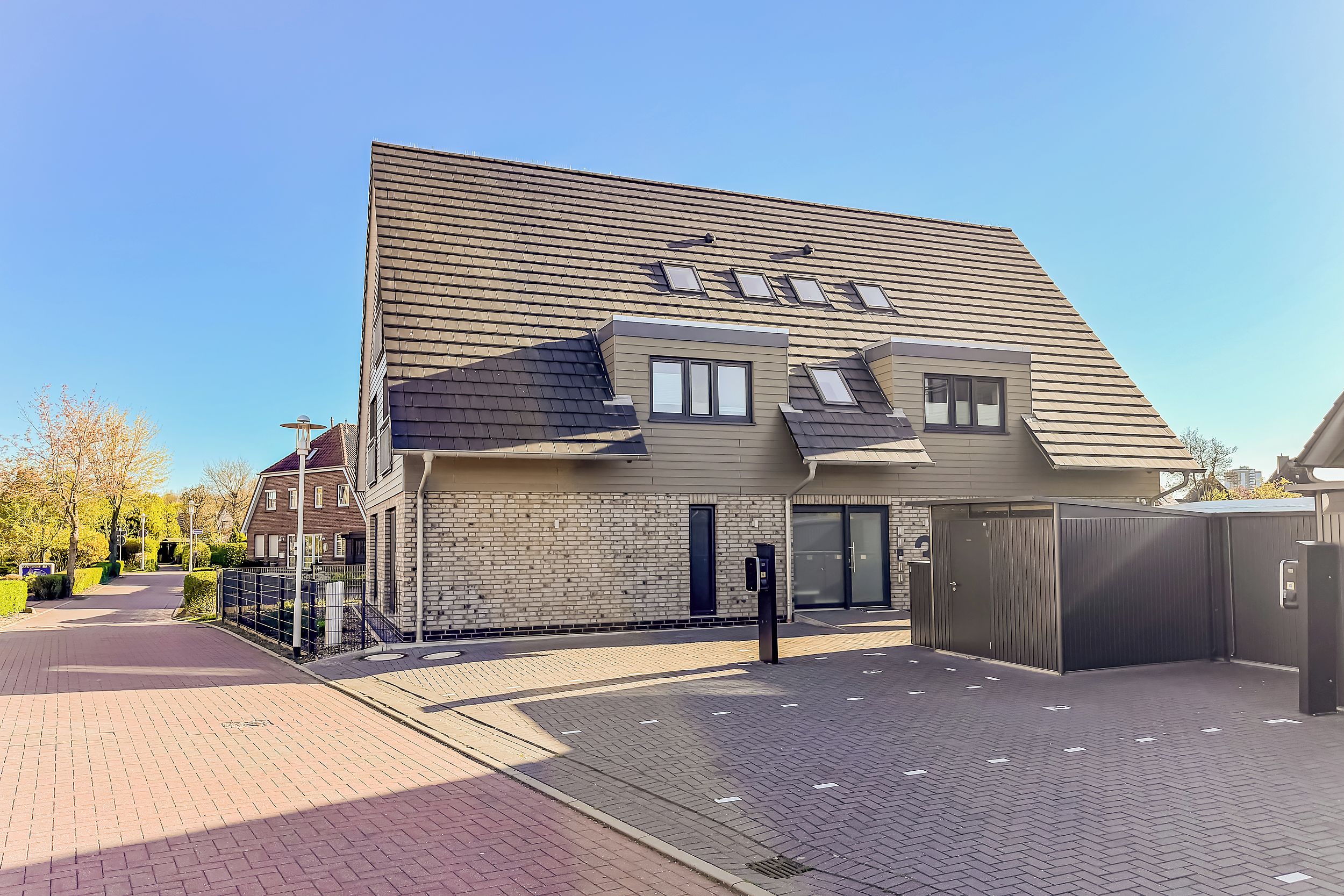 Ein modernes Gebäude mit geneigtem Dach, einer Ziegel-Fassade und einem befestigten Eingang.