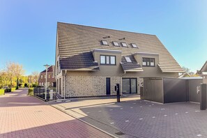 Ein modernes Gebäude mit geneigtem Dach, einer Ziegel-Fassade und einem befestigten Eingang.