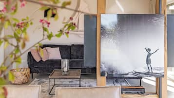 A living room with a sofa, a coffee table, and a painting of a child on a beach.