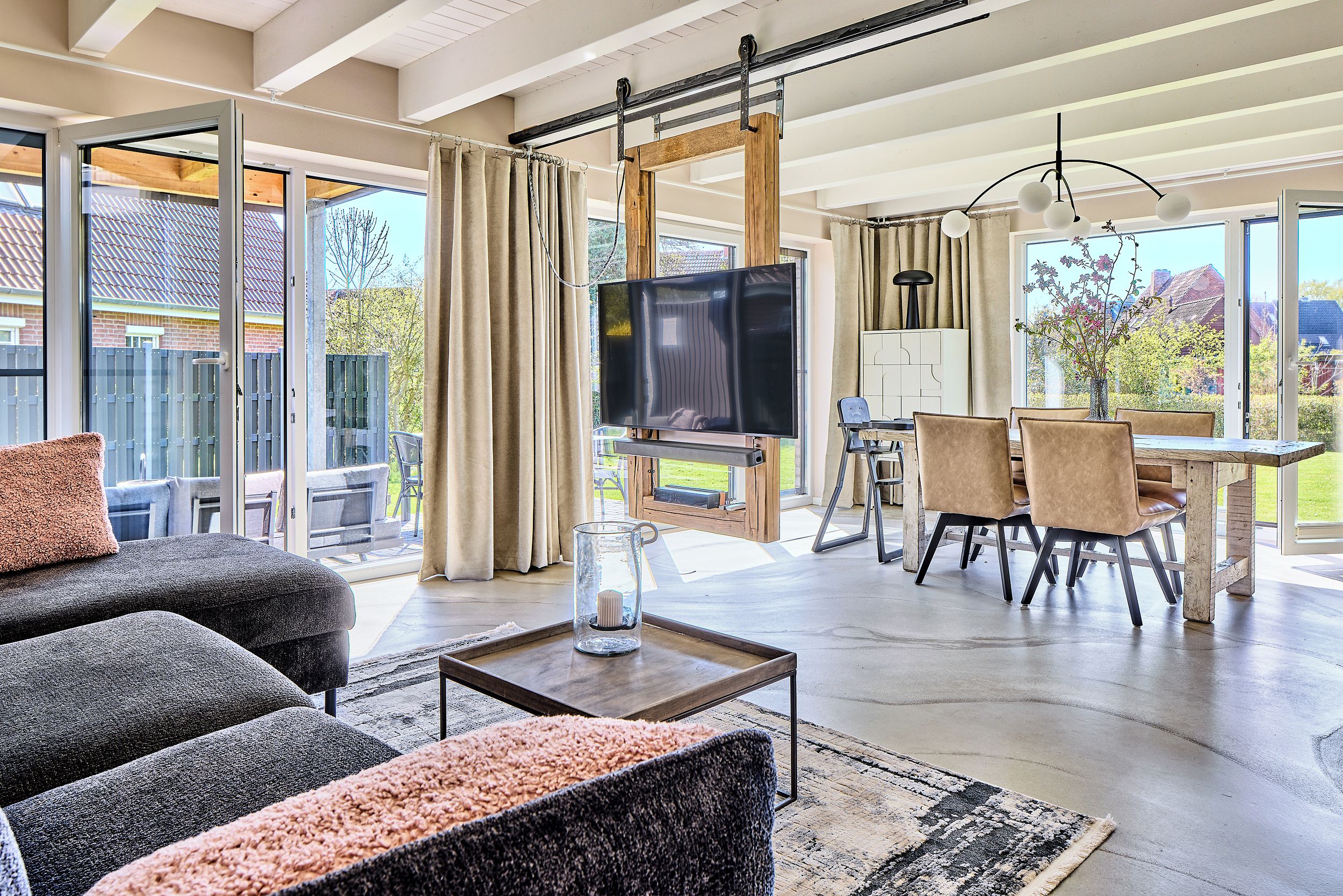 A spacious living room with a large TV, comfortable seating, and a dining area with natural light.