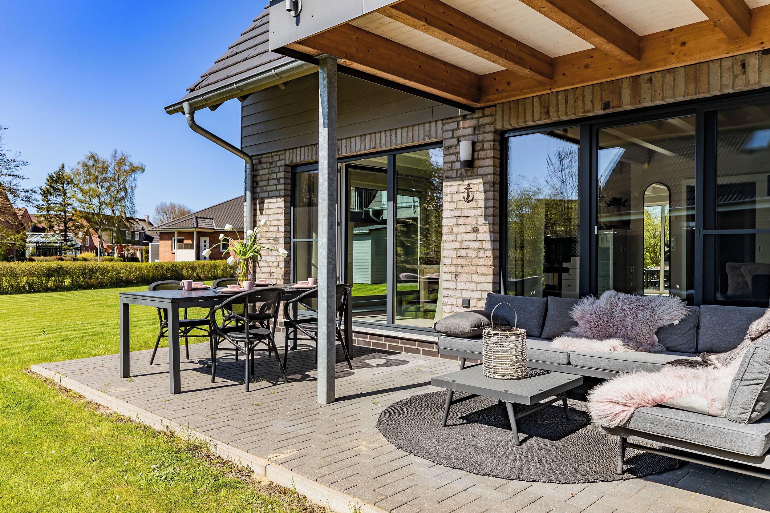 Eine moderne Terrassenanlage im Freien mit Esstisch, Stühlen und einer Couch.