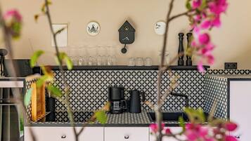 A kitchen with a coffee machine, wine glasses, and a blackboard on the wall.