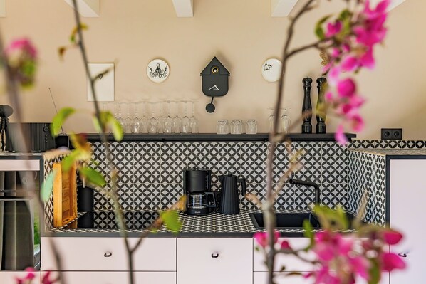 A kitchen with a coffee machine, wine glasses, and a blackboard on the wall. - Grosse Freiheit – stylish ground-floor apartment, quiet location, sleeps up to 4 (Büsum)