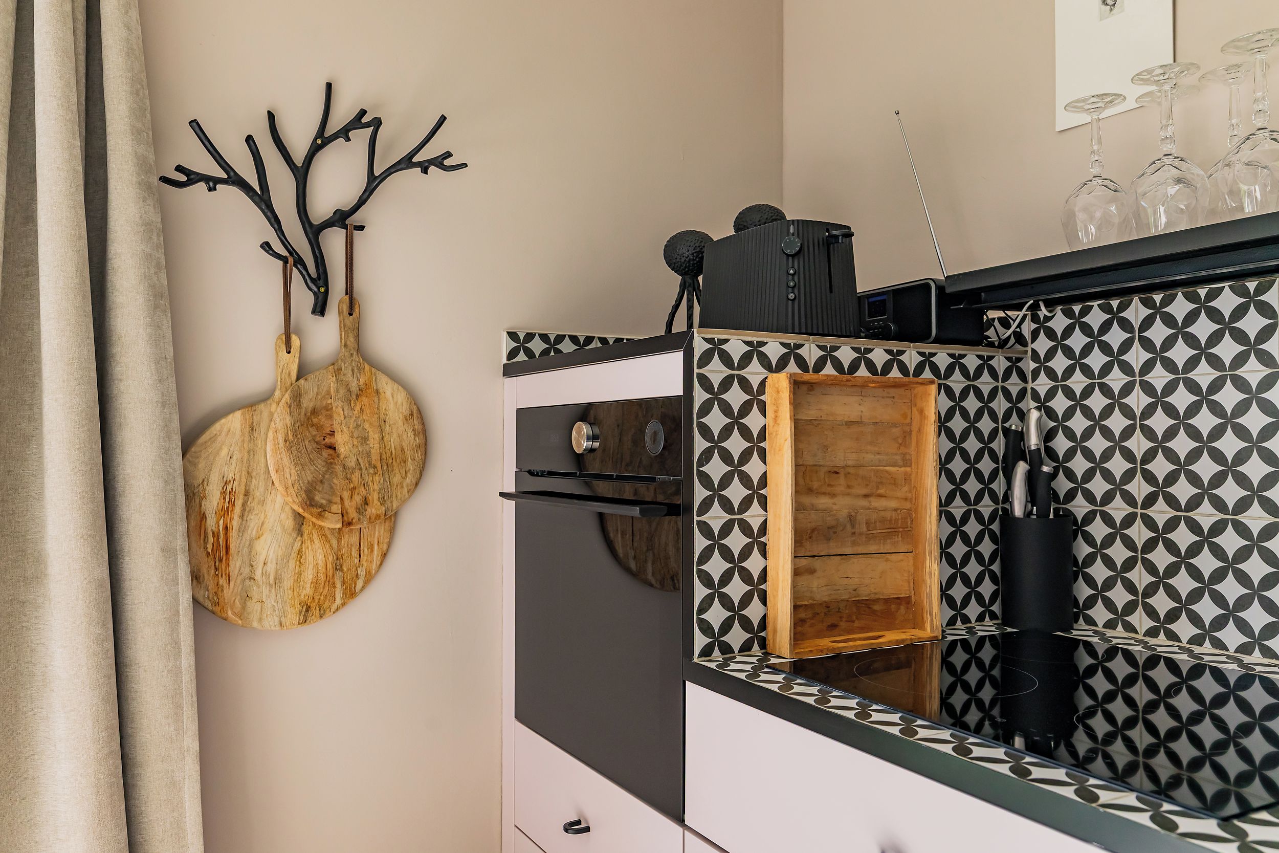 A kitchen with a patterned backsplash, a wooden cutting board, and a wine rack.