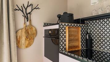 A kitchen with a patterned backsplash, a wooden cutting board, and a wine rack.