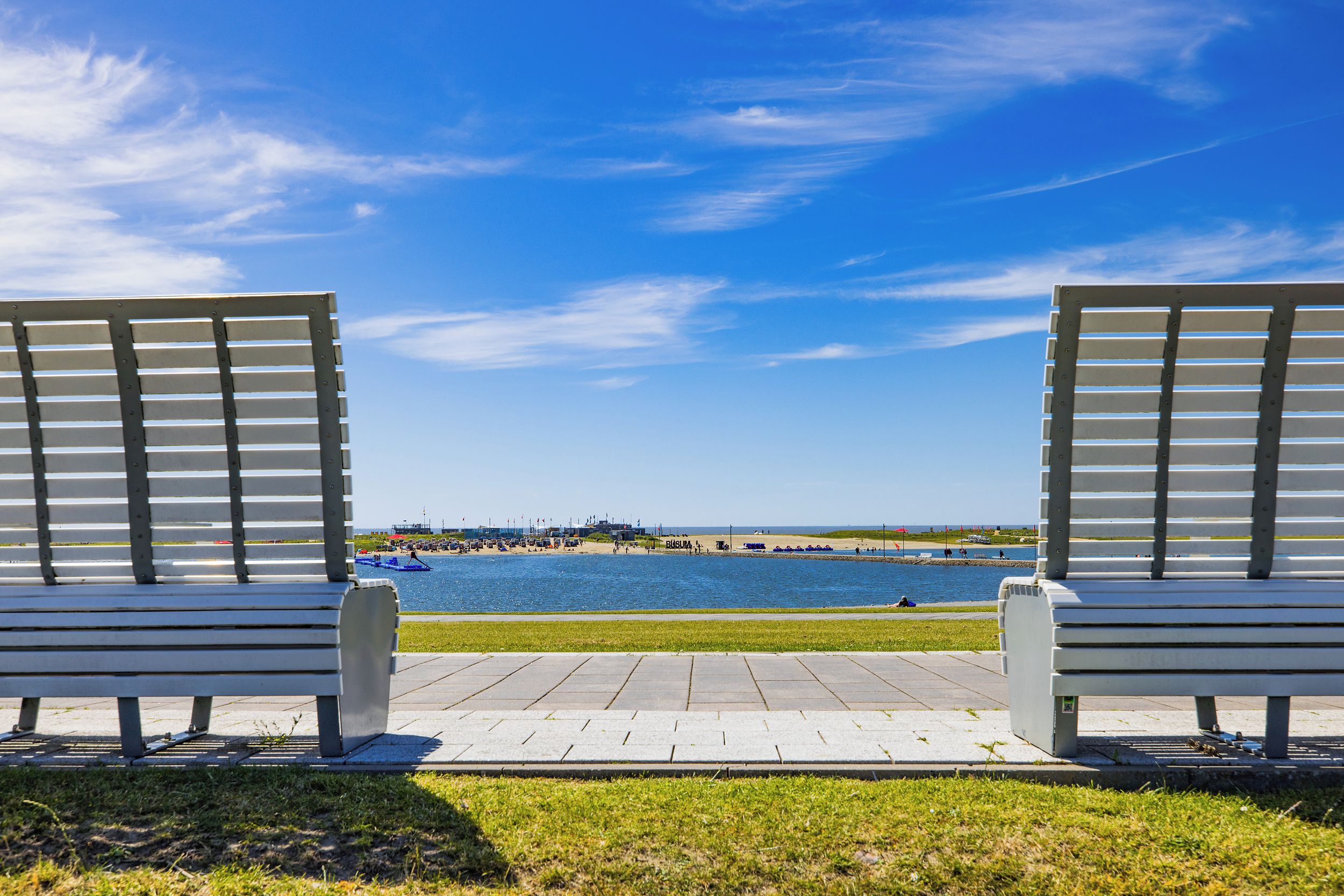 A view from a bench overlooking a beach with a clear sky.