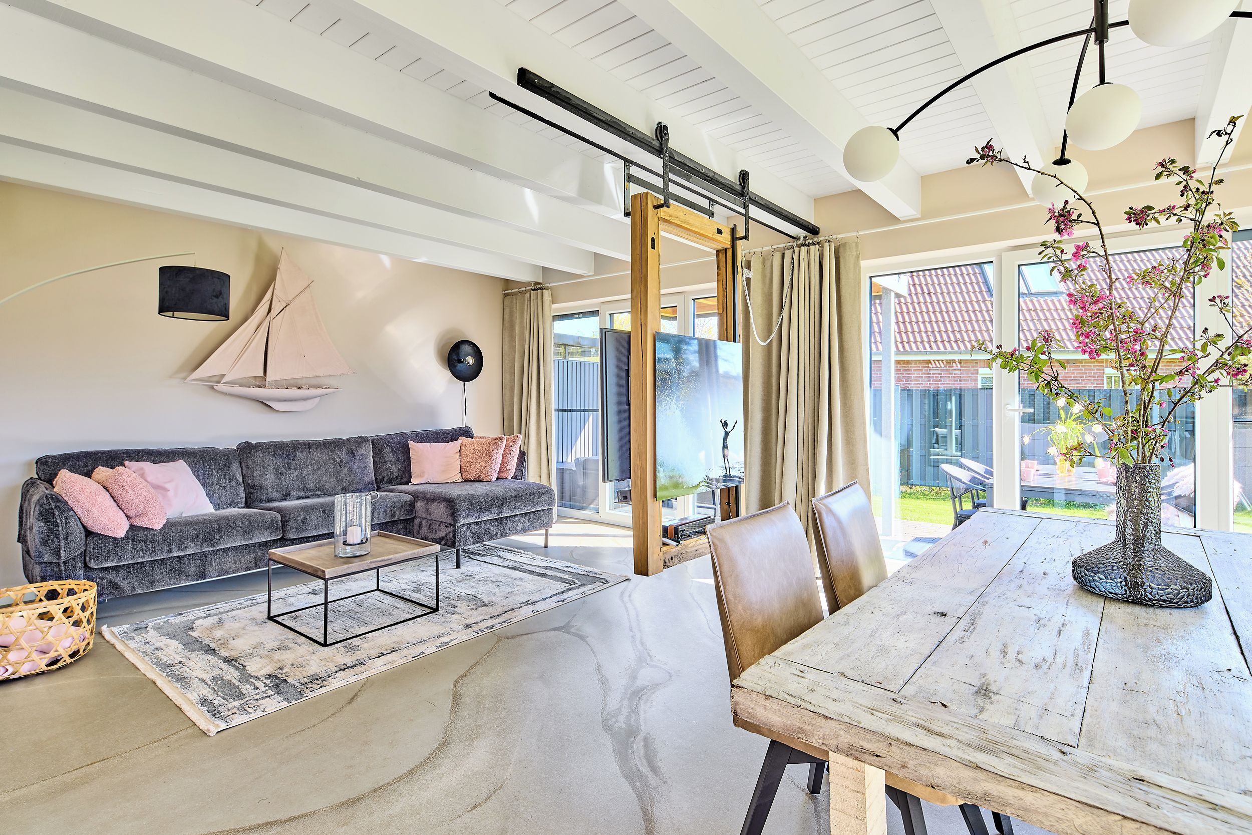En moderne stue med sofa, sofabord og spisebord med stole.