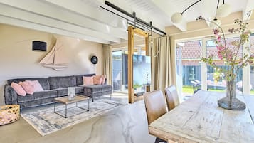 En moderne stue med sofa, sofabord og spisebord med stole.
