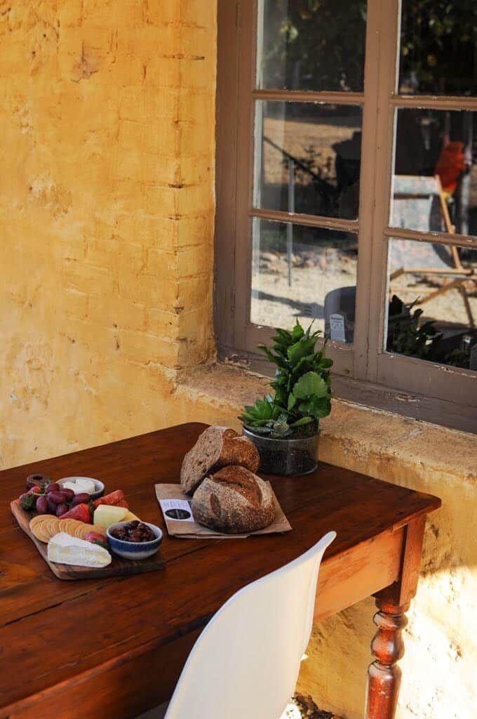 Une table en bois sur laquelle sont disposés divers aliments, une plante en pot et une fenêtre donnant sur l’extérieur.