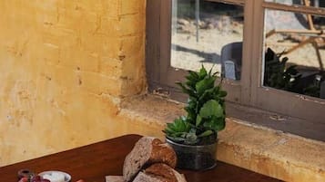 Une table en bois sur laquelle sont disposés divers aliments, une plante en pot et une fenêtre donnant sur l’extérieur.