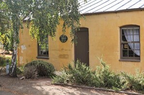 Un bâtiment jaune avec une porte et des fenêtres, entouré de verdure.