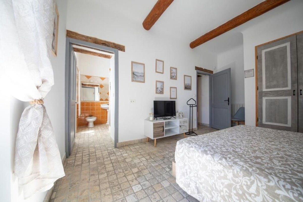 A bedroom with a bed, a television, a wardrobe, and a bathroom visible through an open door.