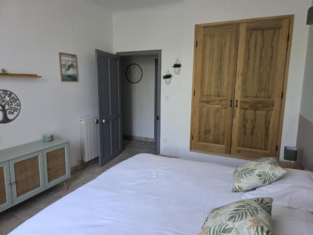 Une chambre à coucher comprenant un lit, une armoire, un radiateur et une porte donnant sur une autre pièce.