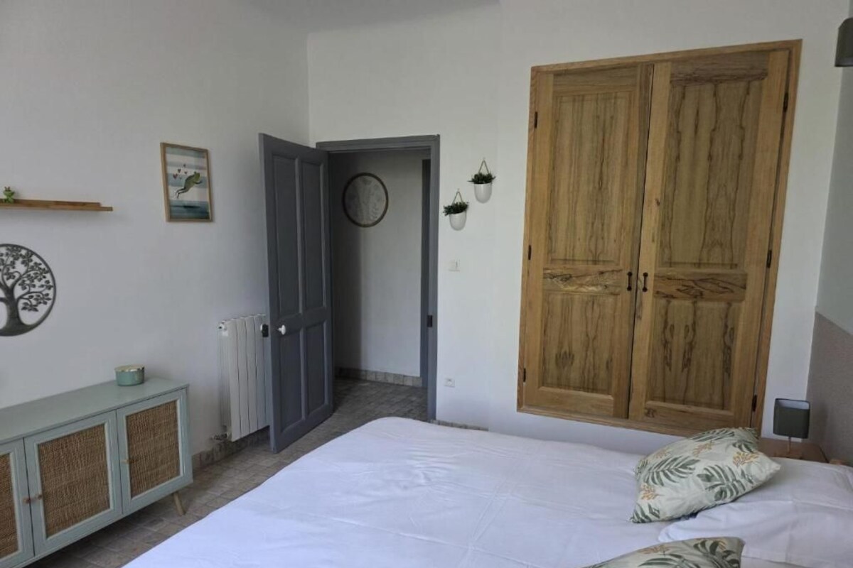 A bedroom with a bed, a wardrobe, a radiator, and a door leading to another room.
