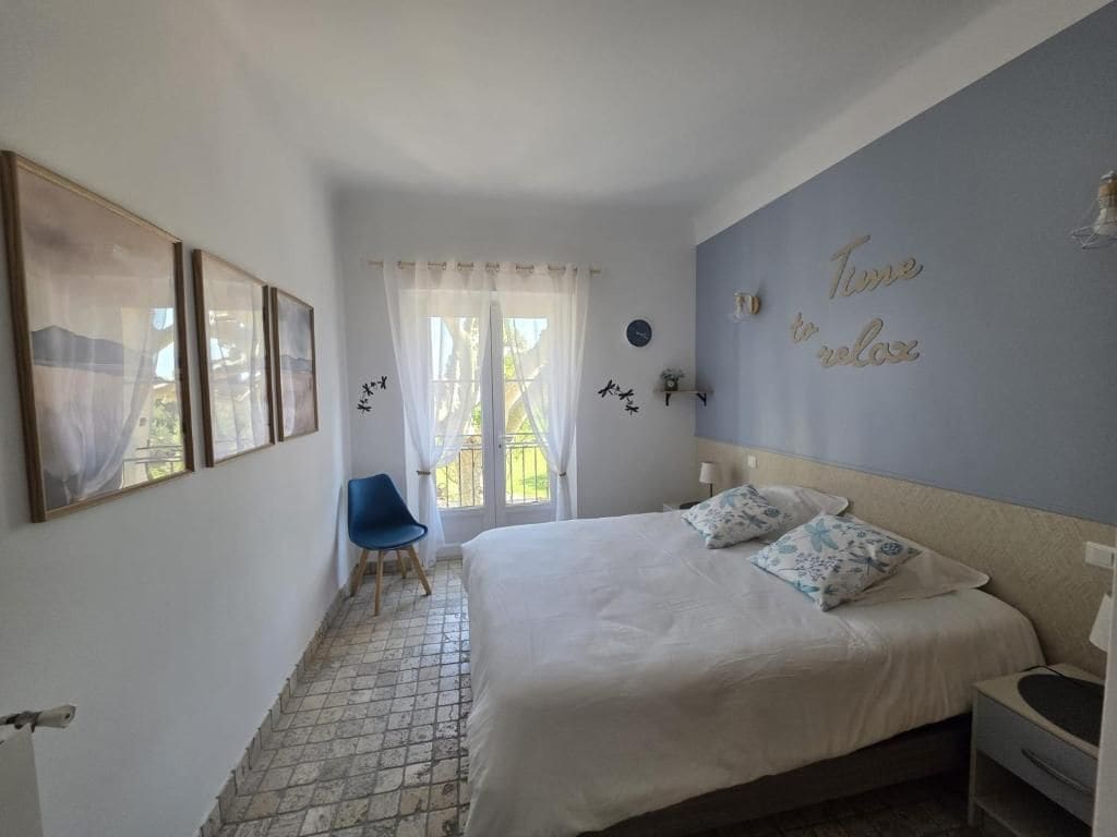 Een slaapkamer met een bed, een stoel en een raam met gordijnen.