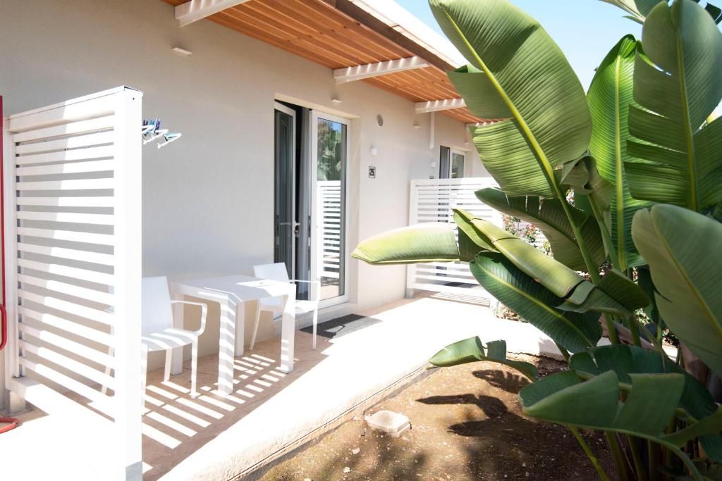 Un área de estar exterior moderna con sillas blancas y una pérgola de madera.