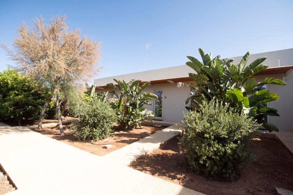 A building with a flat roof, surrounded by a garden with various shrubs and a tree.