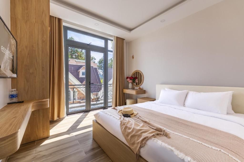 A hotel room with a large bed, a wooden nightstand, a round mirror, and a view of the outside through a sliding glass door.