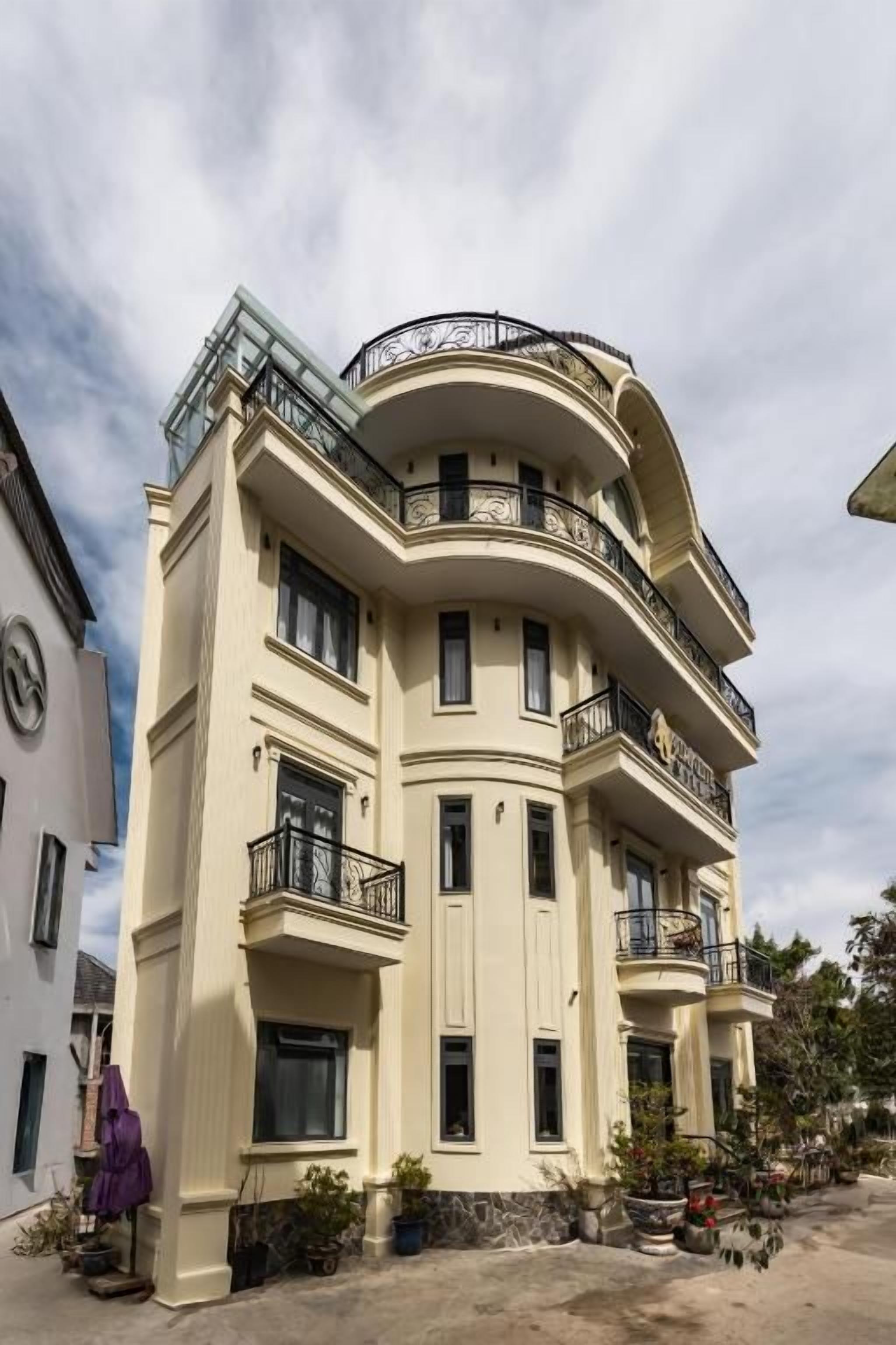 A multi-story building with balconies, a curved facade, and a clear sky.