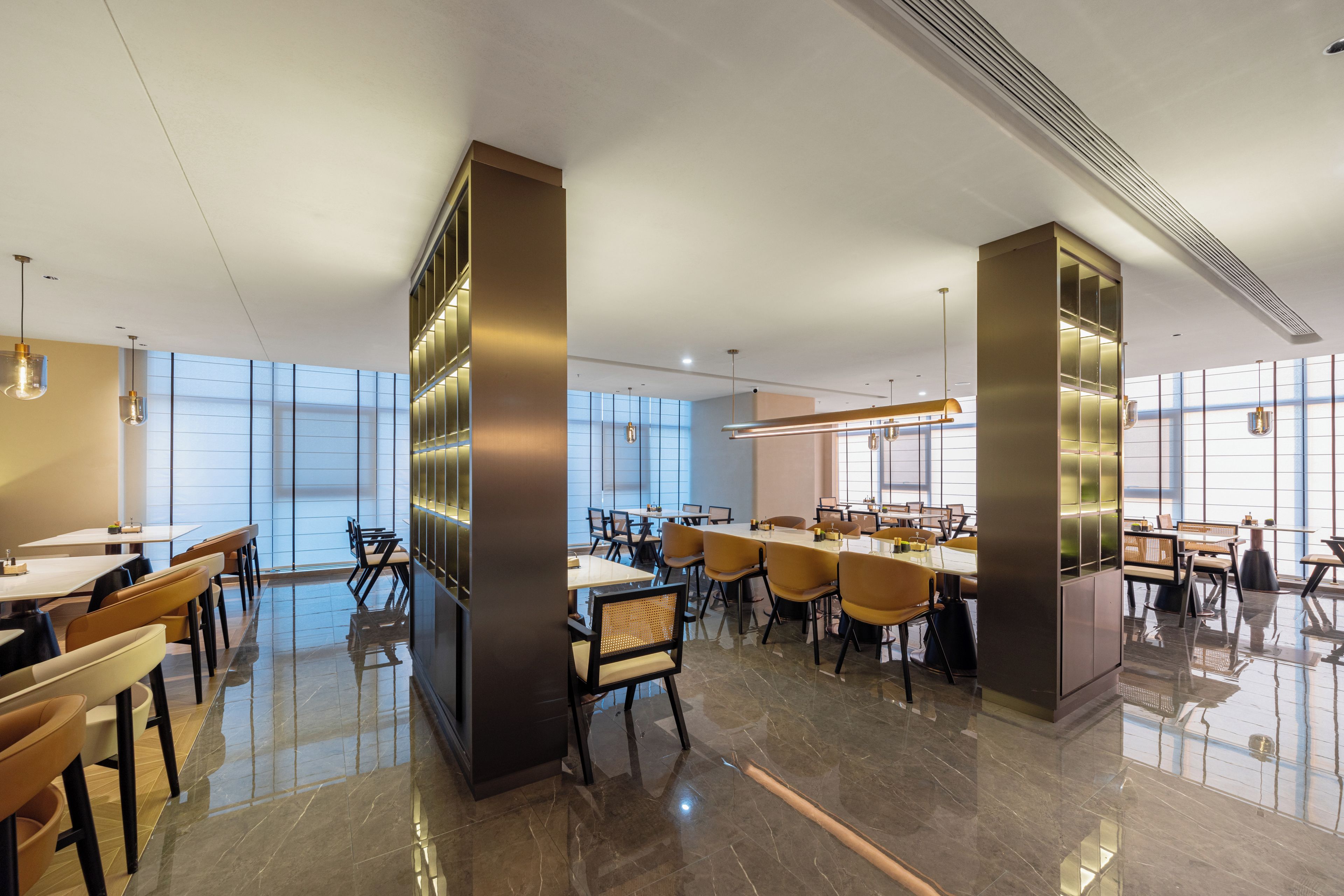 A modern hotel lobby with a spacious layout, featuring a mix of seating arrangements and a large central table.