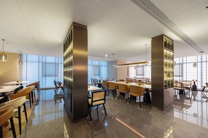 A modern hotel lobby with a spacious layout, featuring a mix of seating arrangements and a large central table.