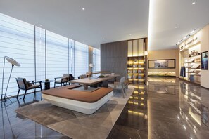 Un moderno vestíbulo de hotel con área de descanso, una recepción y exhibición de servicios.