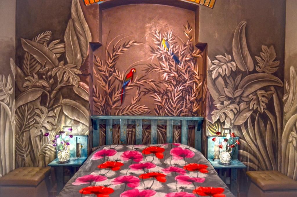 Quarto com cama, mesa de cabeceira e parede com padrão de folhas.