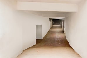 Un pasillo estrecho y recto con paredes blancas y suelo de madera.